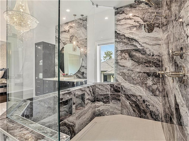 bathroom with a tile shower, vanity, and an inviting chandelier