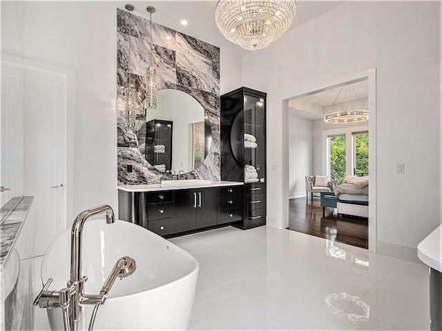 bathroom featuring an inviting chandelier, vanity, tile patterned floors, and a tub