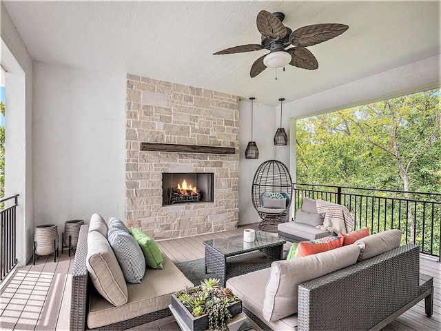 wooden terrace with an outdoor living space with a fireplace and ceiling fan