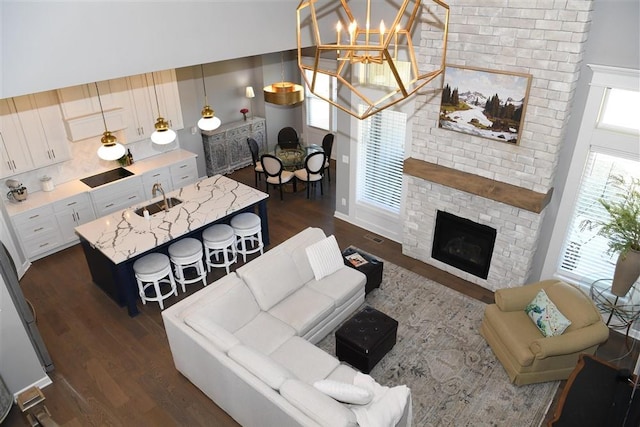 living area featuring dark wood-style floors, a fireplace, and an inviting chandelier