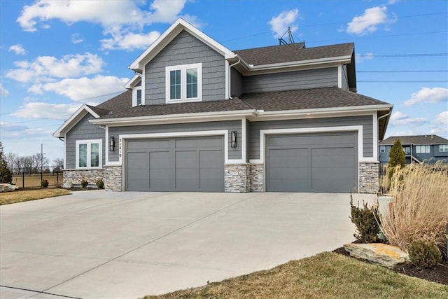 craftsman-style house featuring a shingled roof, stone siding, and driveway