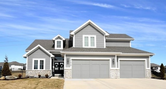 craftsman inspired home featuring concrete driveway, fence, stone siding, and a shingled roof