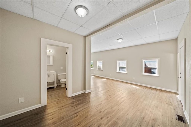 unfurnished room with visible vents, baseboards, a drop ceiling, and wood finished floors