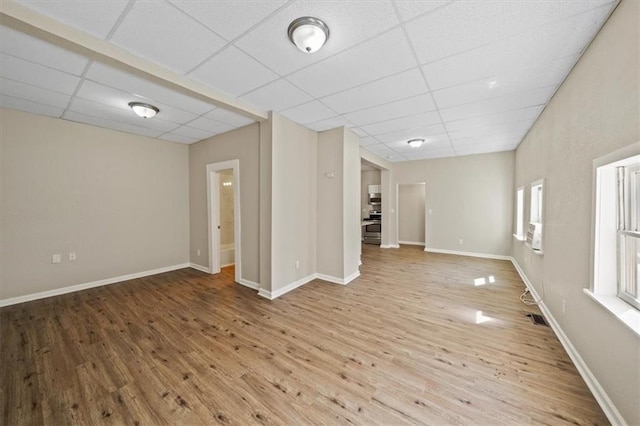 spare room featuring a paneled ceiling, baseboards, and wood finished floors