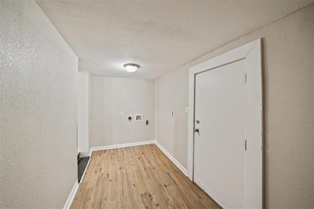 clothes washing area with light wood-style flooring, electric dryer hookup, a textured ceiling, laundry area, and baseboards