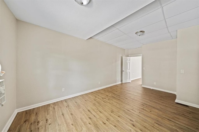 unfurnished room with a drop ceiling, baseboards, and wood finished floors