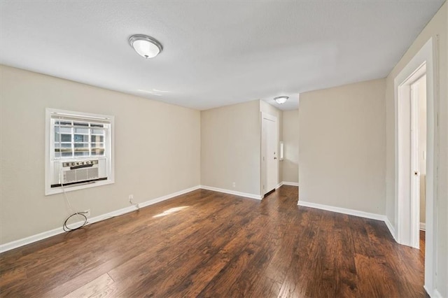 spare room with baseboards, cooling unit, and wood finished floors