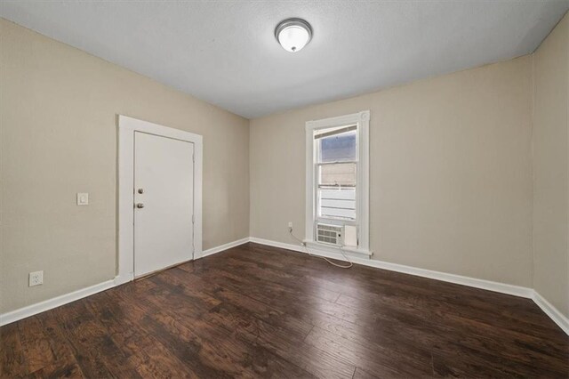 unfurnished room with cooling unit, wood finished floors, and baseboards