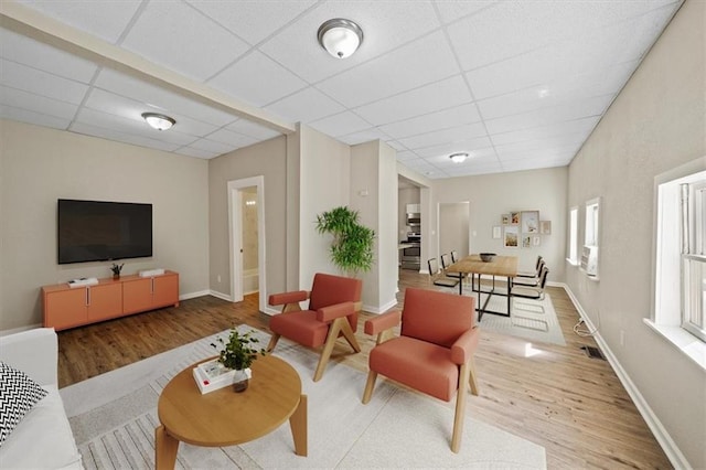 living room with baseboards, a drop ceiling, and wood finished floors