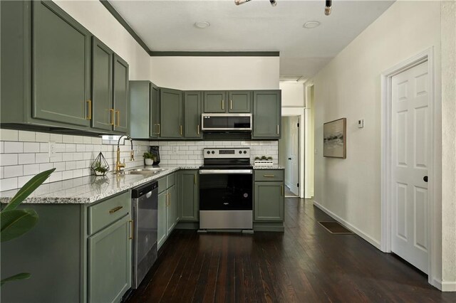 kitchen with green cabinets, dark wood-type flooring, stainless steel appliances, sink, and light stone counters