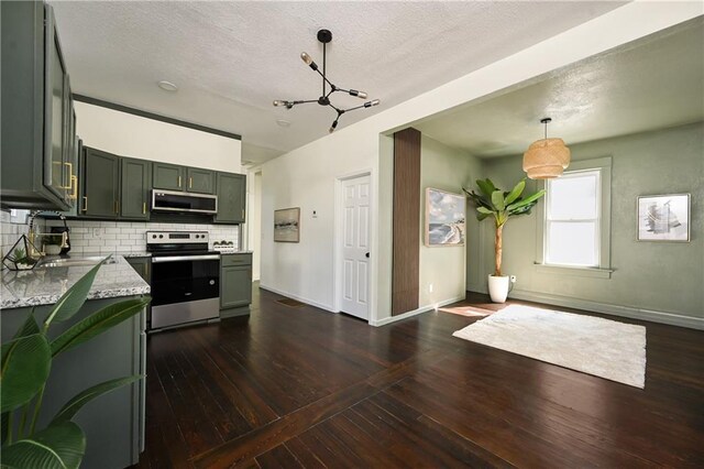 kitchen featuring hanging light fixtures, light stone countertops, stainless steel appliances, sink, and dark wood-type flooring