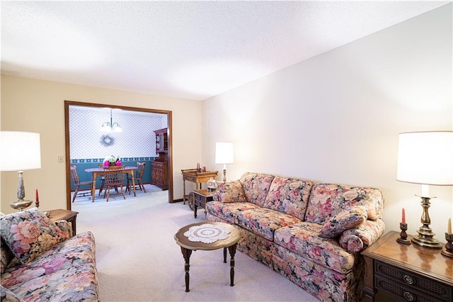 living room featuring an inviting chandelier, carpet, and a textured ceiling