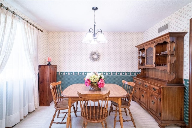 carpeted dining room featuring a chandelier