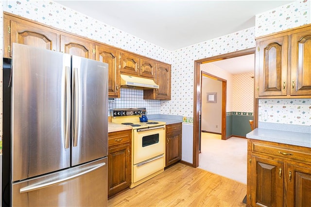 kitchen with decorative backsplash, stainless steel fridge, electric stove, and light hardwood / wood-style floors