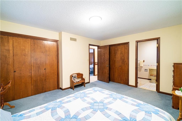 carpeted bedroom featuring ensuite bathroom and a textured ceiling