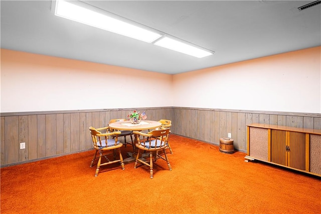 carpeted dining space with wood walls