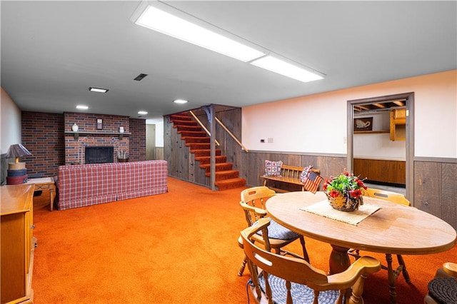 carpeted dining room with a fireplace and wood walls