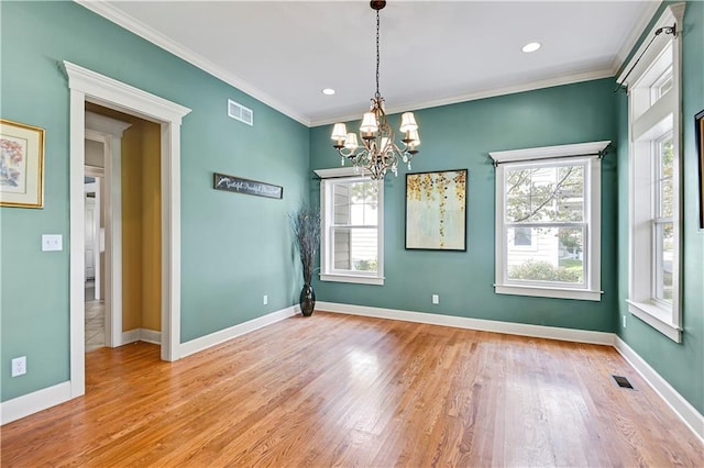 unfurnished dining area featuring crown molding, a notable chandelier, and light wood-type flooring