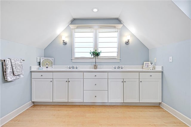 bathroom with hardwood / wood-style floors, vanity, and vaulted ceiling