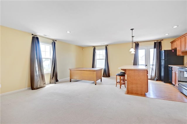 kitchen with a breakfast bar, black appliances, light hardwood / wood-style floors, decorative light fixtures, and a kitchen island