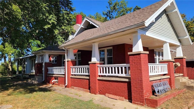 view of side of home featuring covered porch