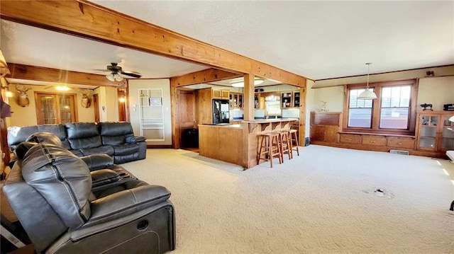 living room with beamed ceiling, ceiling fan, light colored carpet, and indoor bar