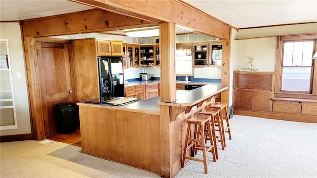 kitchen featuring a breakfast bar, ornamental molding, light colored carpet, and black refrigerator with ice dispenser