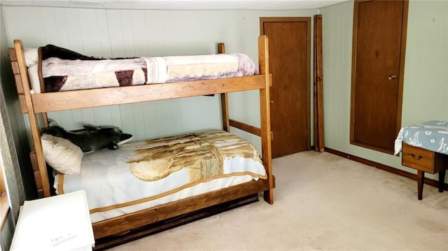 bedroom with wood walls and light carpet