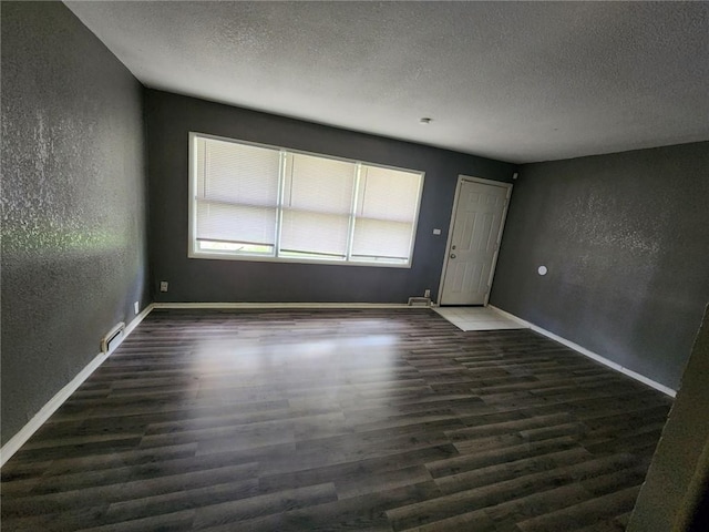 unfurnished room featuring a textured ceiling and dark hardwood / wood-style floors