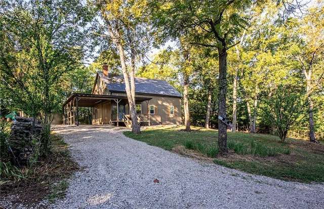 view of front of house featuring a porch, a chimney, and gravel driveway