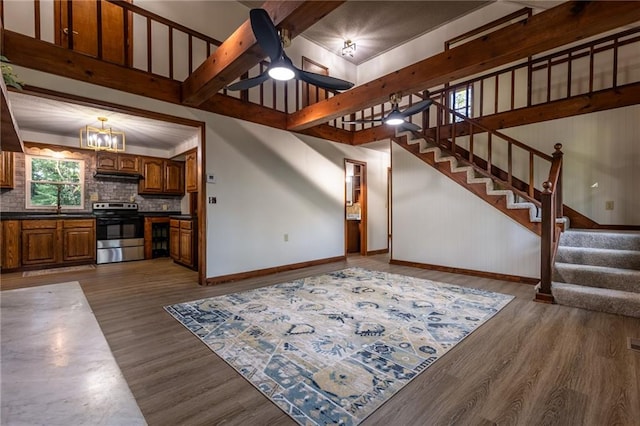 living room with dark hardwood / wood-style floors, ceiling fan with notable chandelier, and beam ceiling