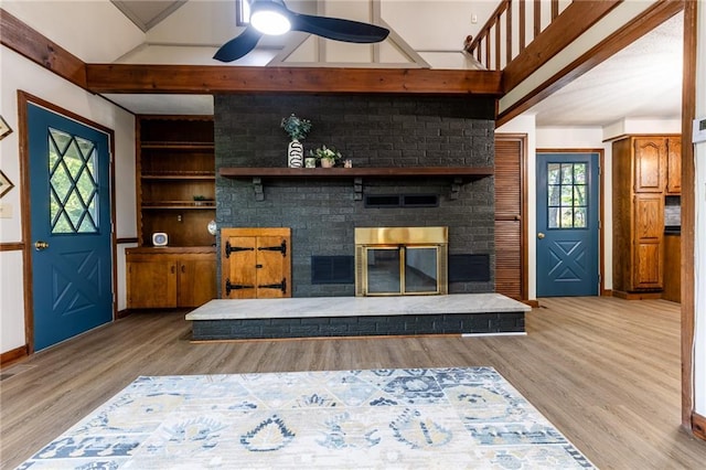 living room with built in features, a ceiling fan, wood finished floors, and a fireplace