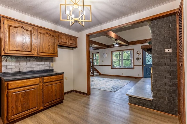 kitchen with light wood-type flooring, ceiling fan with notable chandelier, hanging light fixtures, and a textured ceiling