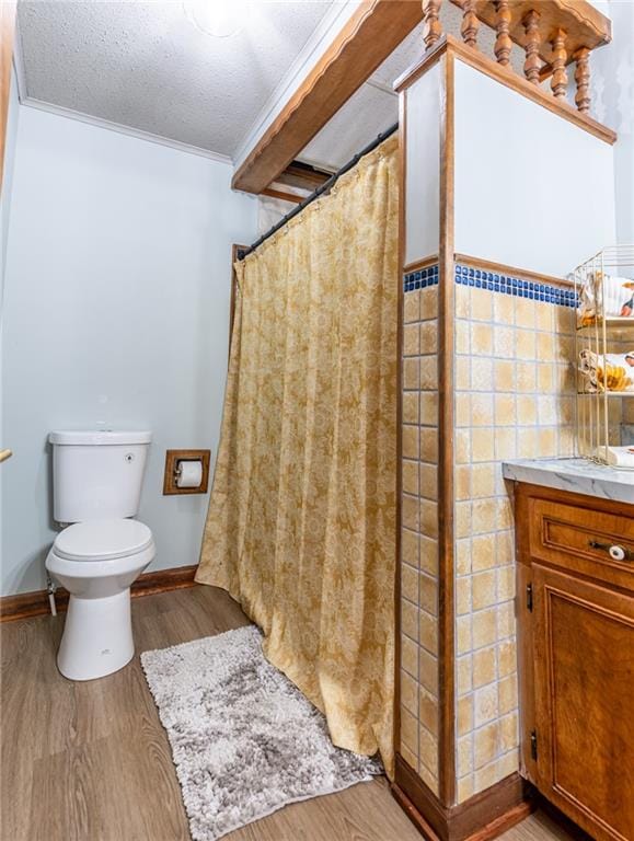 bathroom featuring a textured ceiling, vanity, toilet, ornamental molding, and hardwood / wood-style flooring