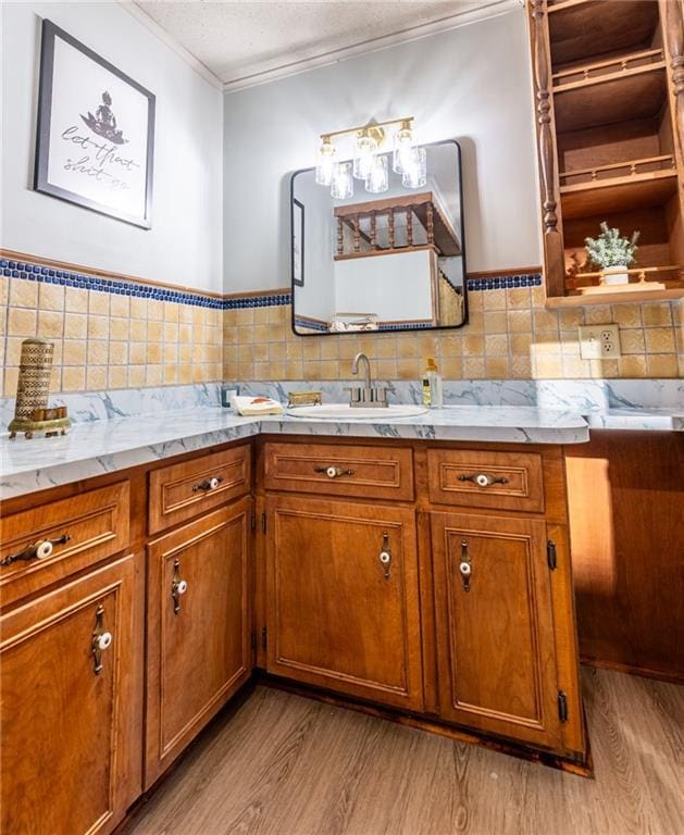 bathroom with a sink, a textured ceiling, wood finished floors, and crown molding