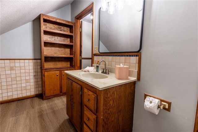 bathroom featuring vanity, a textured ceiling, tasteful backsplash, tile walls, and hardwood / wood-style flooring