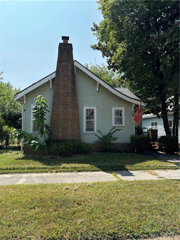 view of side of home with a yard and a chimney