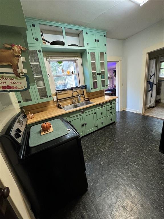 kitchen with washer / dryer, green cabinetry, and sink