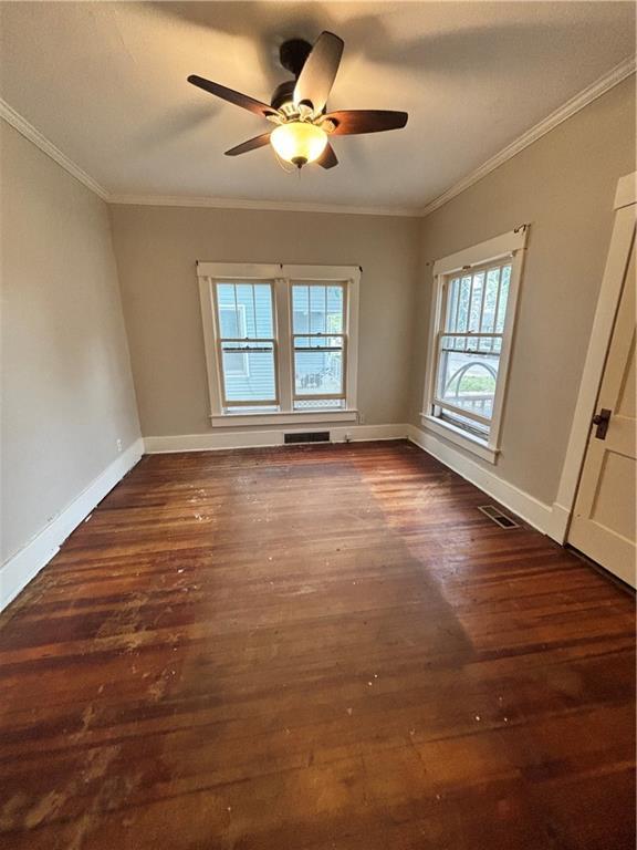 unfurnished room with visible vents, crown molding, baseboards, and dark wood-style flooring