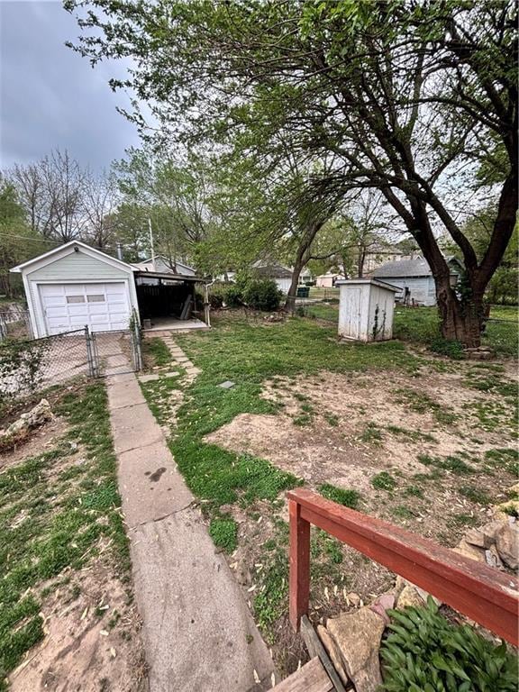 view of yard with fence, a shed, driveway, an outdoor structure, and a garage