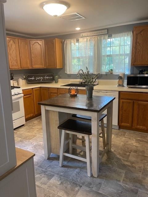 kitchen featuring crown molding, a healthy amount of sunlight, sink, and white appliances