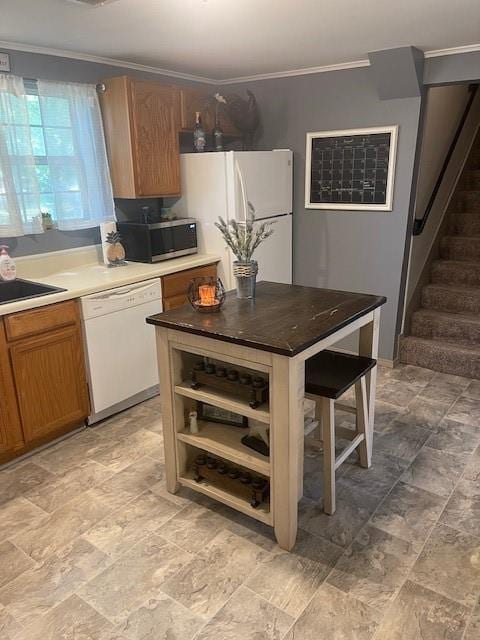 kitchen featuring crown molding, white appliances, sink, a kitchen breakfast bar, and a kitchen island