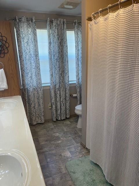 bathroom featuring walk in shower, toilet, and vanity