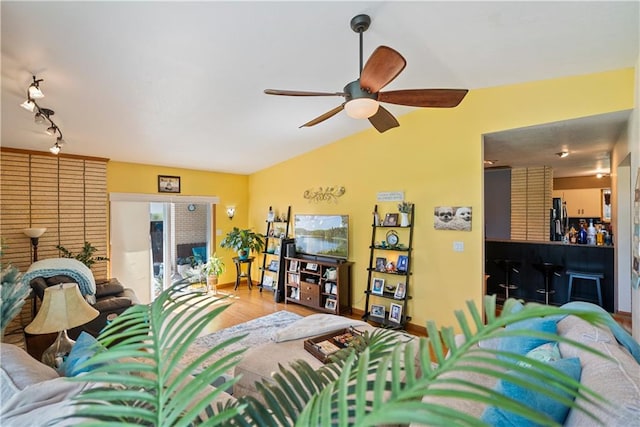 living room with rail lighting, ceiling fan, wood-type flooring, and vaulted ceiling