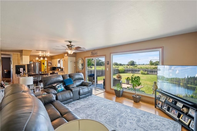 living room featuring a wealth of natural light, ceiling fan with notable chandelier, and light hardwood / wood-style floors