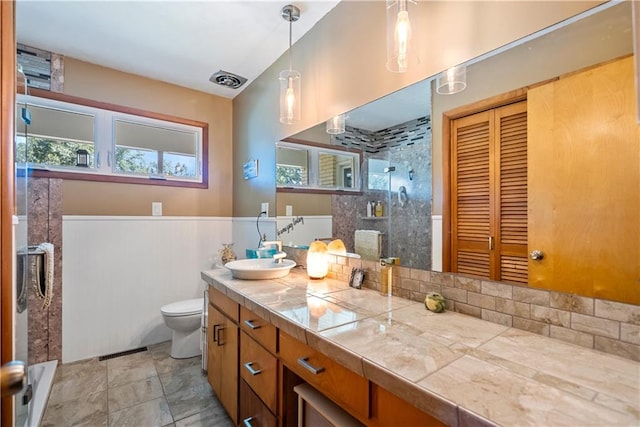 bathroom with a shower with door, vanity, and toilet