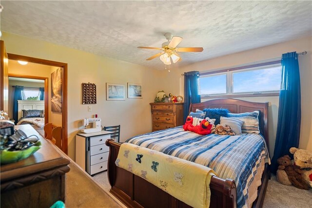 bedroom featuring a textured ceiling, ceiling fan, and light carpet