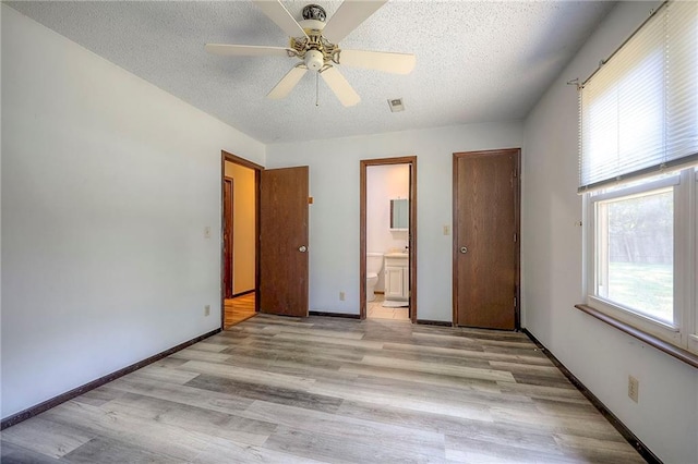 unfurnished bedroom with ceiling fan, a textured ceiling, ensuite bath, and light hardwood / wood-style flooring