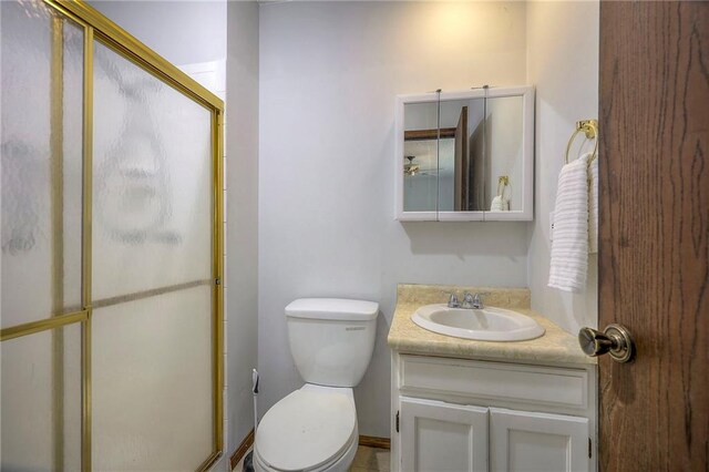 bathroom featuring toilet, an enclosed shower, and vanity