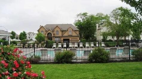 community pool featuring a lawn, a patio, and fence